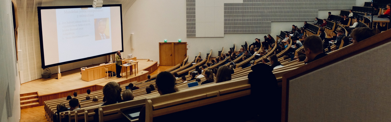 Titelbild Campus Management Menschen sitzen in einem Hörsaal und hören einem Vortrag zu.